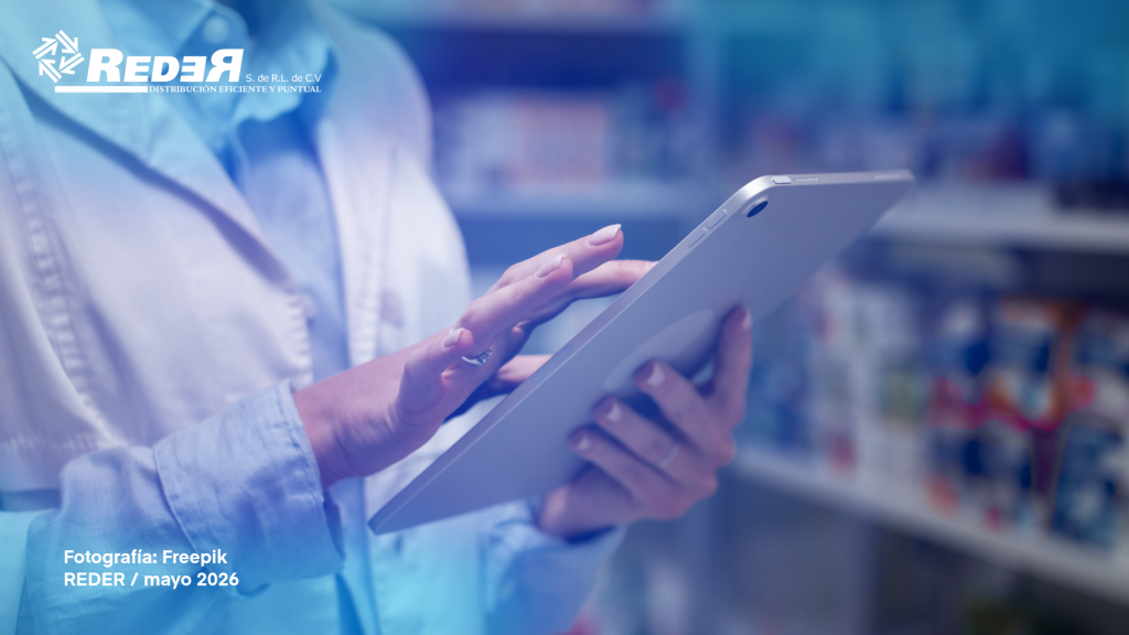 Farmacéutico utilizando tablet o computadora en mostrador de farmacia moderna con estantes de medicamentos al fondo.