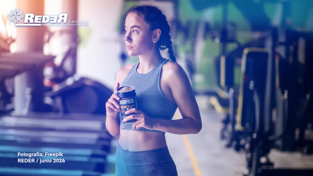 Deportista en gimnasio moderno en fase de preparación pre-entrenamiento con suplemento o bebida de cafeína en primer plano.